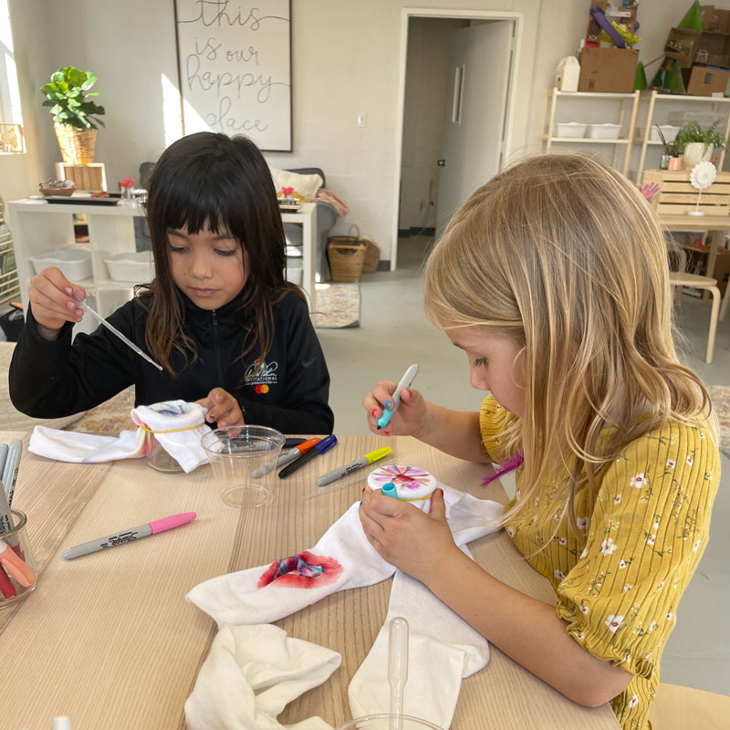 two girls doing a craft at the table