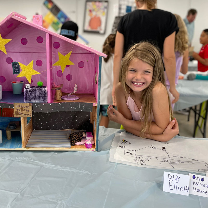 girl posing with doll house architecture project